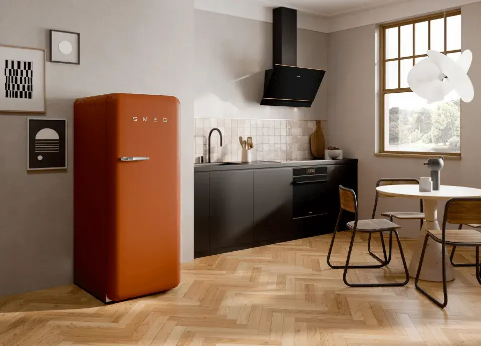 Rostfarbener Retro-Kühlschrank von smeg Solo-Stand-Gerät neben kurzer schwarzer Küchenzeile runder Esstisch mit Design Hängeleuchte Parkettboden